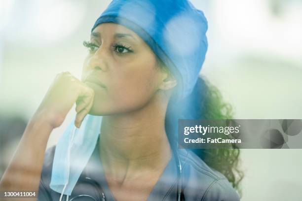 female nurse thinking about the pandemic situation - serviços essenciais imagens e fotografias de stock