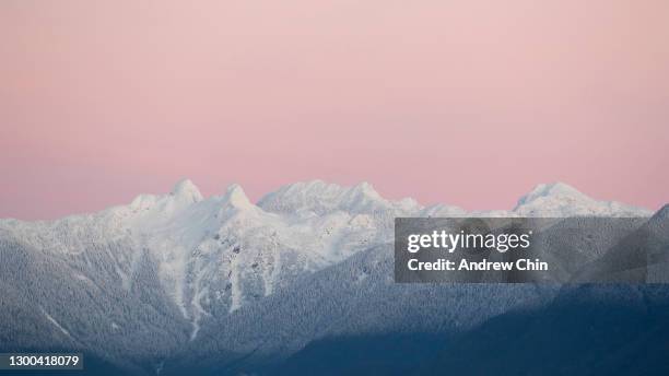 Two pointed peaks known as "The Lions" are seen shortly before sunrise as the sky glows pink on February 03, 2021 in Burnaby, British Columbia,...