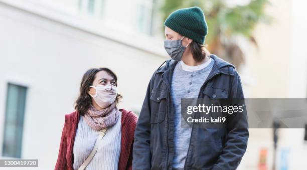 young couple walking in city, wearing face masks - woman taller than man stock pictures, royalty-free photos & images