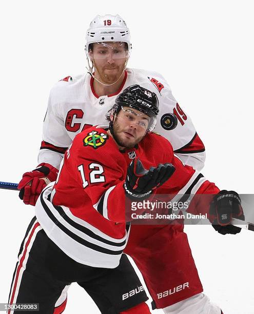 Alex DeBrincat of the Chicago Blackhawks catches an airborne puck in front of Dougie Hamilton of the Carolina Hurricanes at the United Center on...