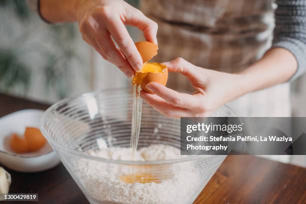 hands breaking a egg in a bowl with flour - mixing stock pictures, royalty-free photos & images