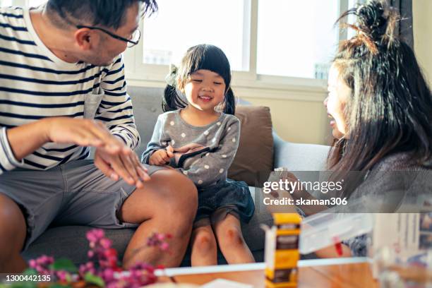 asian family mother putting band aid for her daughter and father comforting  his daughter as well - asian family fall stock-fotos und bilder