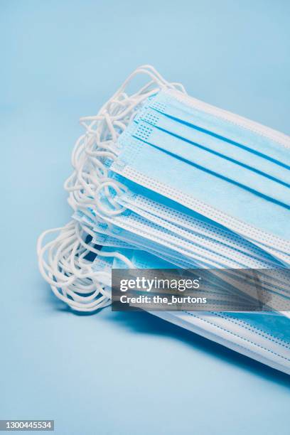 high angle view of a lot of blue surgical face masks on a stack on blue background - face mask coronavirus stock-fotos und bilder