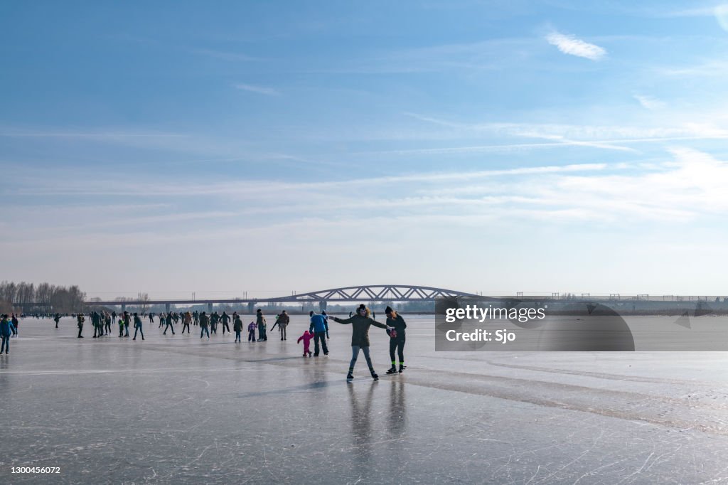 People ice skating on a frozen lake next to the river IJssel near Zwolle