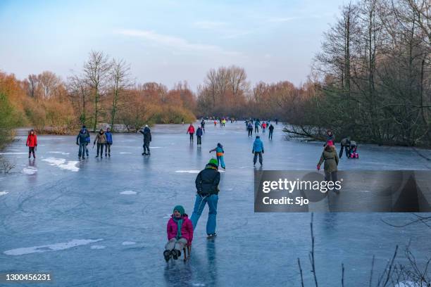 people ice skating on a frozen lake next to the river ijssel near zwolle - hockey skate stock pictures, royalty-free photos & images