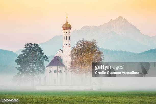 church of st coloman in the fog, hohenschwangau, bavaria, germany - neuschwanstein stock-fotos und bilder