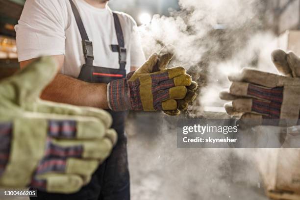 cleaning dirt from gloves in a warehouse! - dirty construction worker stock pictures, royalty-free photos & images