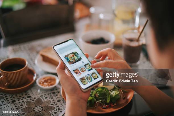 vista ad alto angolo mano della donna cinese asiatica sull'app mobile per la consegna di cibo online durante l'orario di colazione - cibo foto e immagini stock