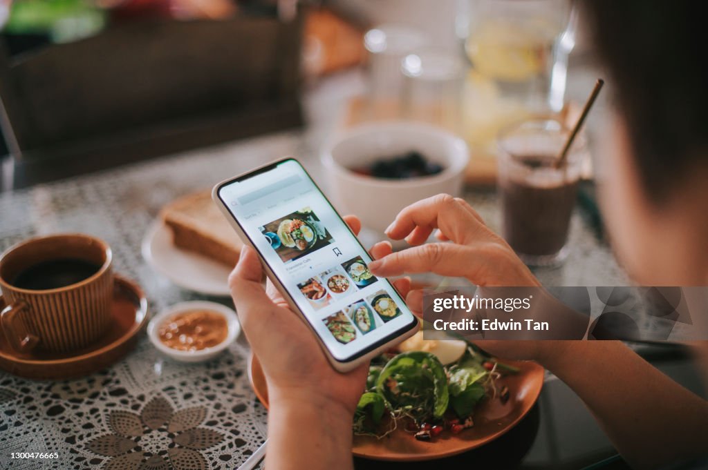 High angle view asian chinese woman's hand on mobile app for online   food delivery during breakfast time