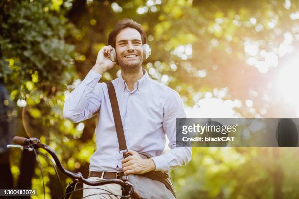 portrait of a young businessman on a bicycle - podcast headphones stock pictures, royalty-free photos & images