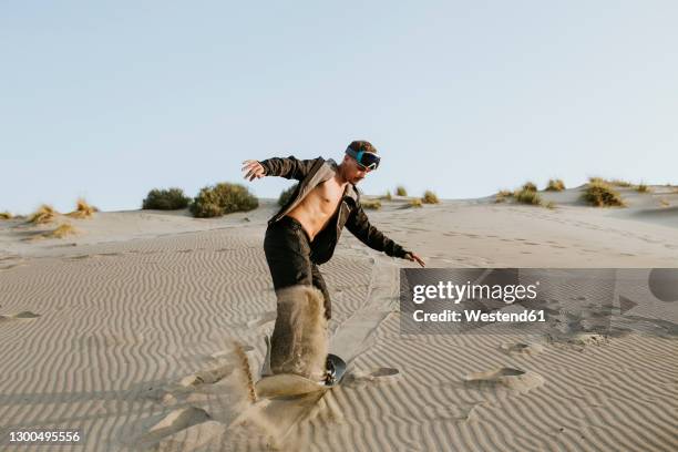 young man snow boarding on sand at almeria, tabernas desert, spain - sand boarding stock pictures, royalty-free photos & images