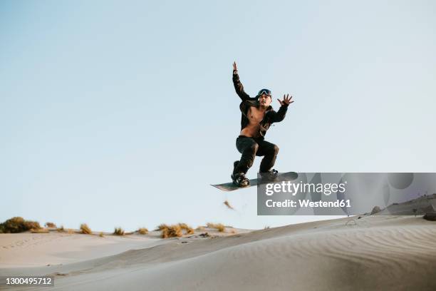 man sandboarding over sand dunes at almeria, tabernas desert, spain - sand boarding stock pictures, royalty-free photos & images