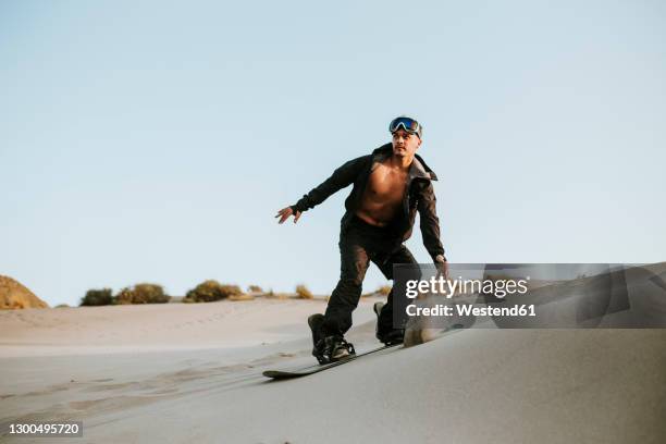 young man sandboarding in desert at almeria, tabernas, spain - sand boarding stock pictures, royalty-free photos & images
