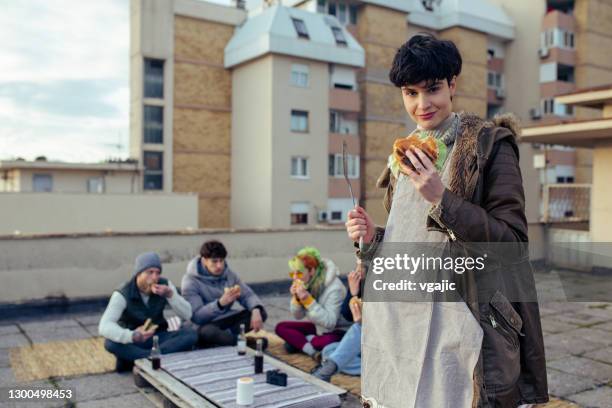 belle jeune femme mangeant le hamburger à la partie de toit - burger portrait photos et images de collection