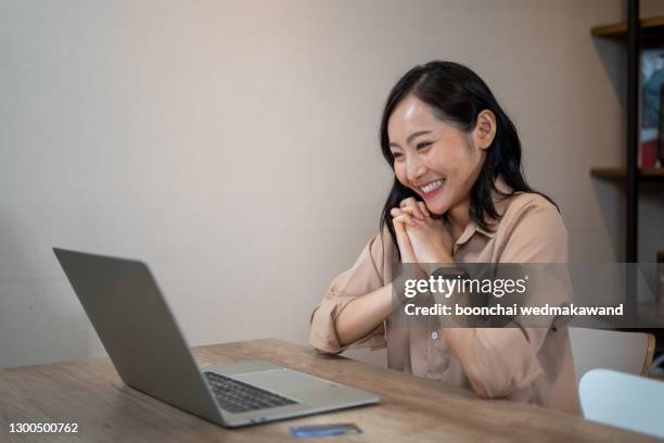 happy young indian business woman entrepreneur using computer looking at screen working in internet sit at office desk, smiling female professional employee typing email on laptop at workplace - business person handing over a letter fotografías e imágenes de stock