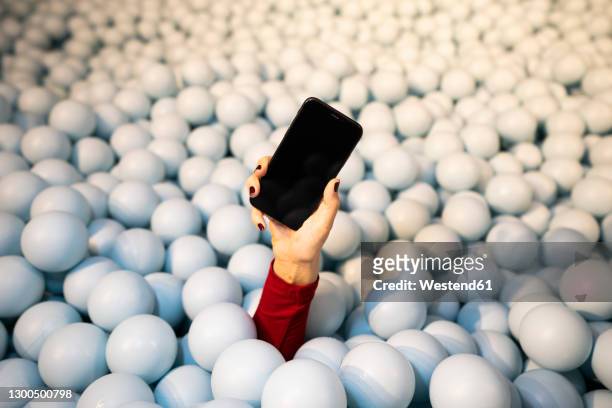 hand of young woman holding mobile phone in ball pit - adult ball pit stock pictures, royalty-free photos & images