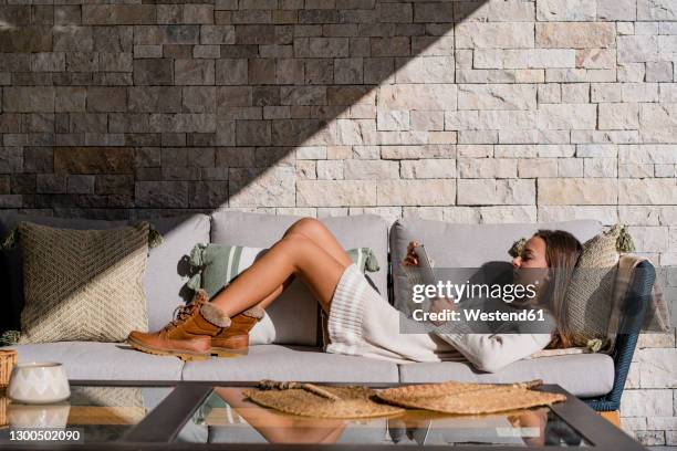 teenage girl using digital tablet while lying on sofa at home - lying on back girl on the sofa stock pictures, royalty-free photos & images