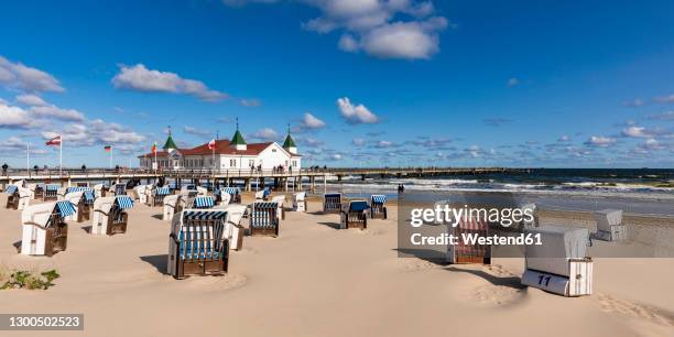 germany, mecklenburg-western pomerania, heringsdorf, hooded beach chairs on empty beach with ahlbeck pier in background - usedom 個照片及圖片檔