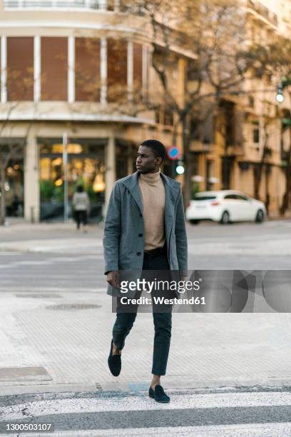 man wearing jacket looking away while walking on road - fashionable man stock pictures, royalty-free photos & images