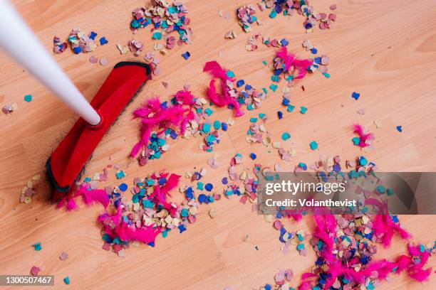 cleaning confetti and pink feathers after party on hardwood floor - cleaning up after party stock-fotos und bilder