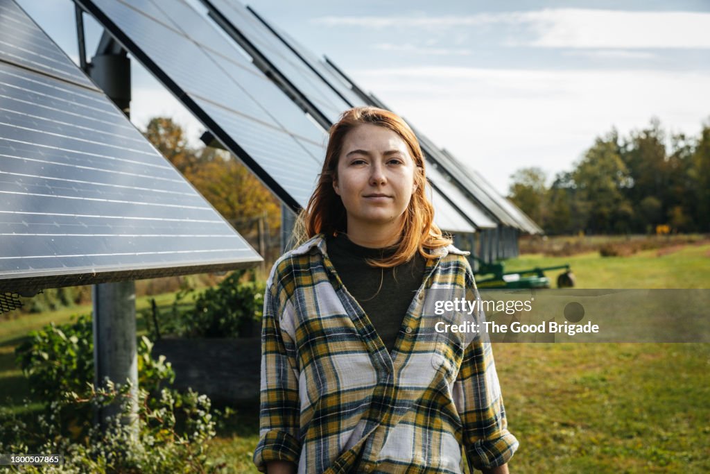 Young woman standing in front of solar panels on farm