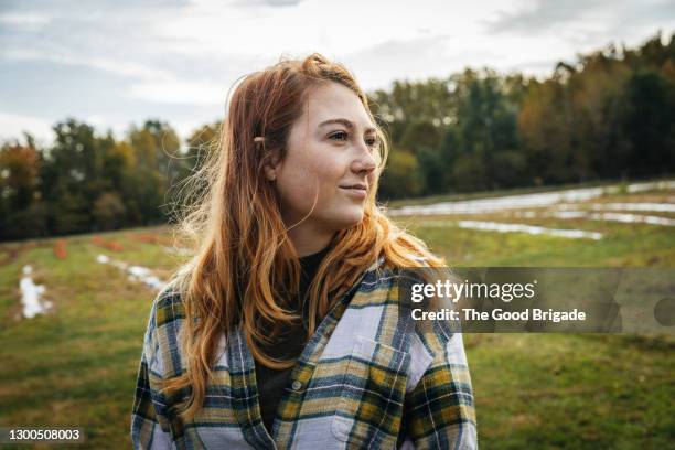 portrait of young woman standing on field at farm - farmer female confident stock-fotos und bilder