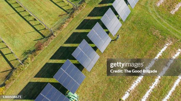 overhead shot of woman walking near solar panels on farm - grünes wirtschaften stock-fotos und bilder