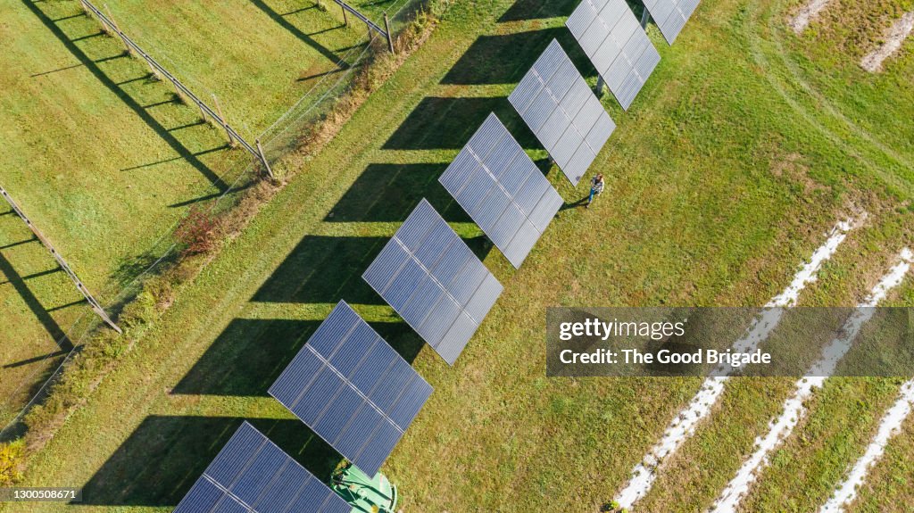 Overhead shot of woman walking near solar panels on farm