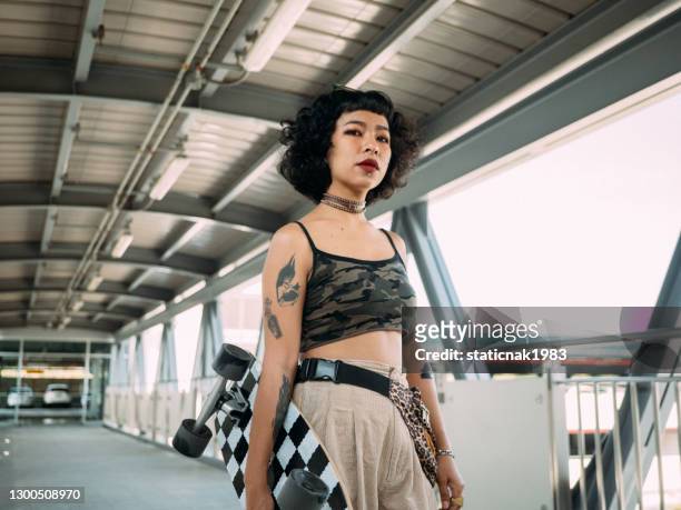 hipster femmes asiatiques vont jouer à la planche à roulettes. - tatouage femme photos et images de collection
