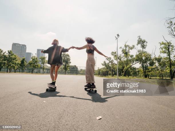 young girls with riding longboard with friends - skating stock pictures, royalty-free photos & images