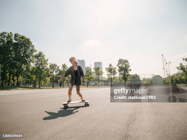 teenager-mädchen mit skateboard im park an einem sonnigen tag. - longboard skating stock-fotos und bilder