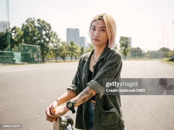 adolescente con monopatín en el parque en un día soleado. - thai ethnicity fotografías e imágenes de stock