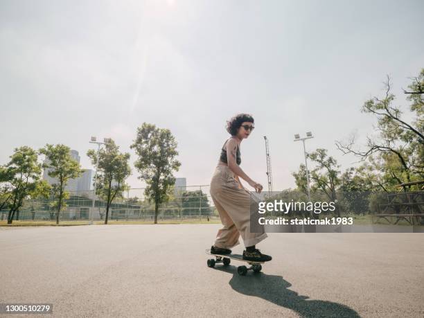 teenage girl with skateboard in the park on a sunny day. - skating stock pictures, royalty-free photos & images