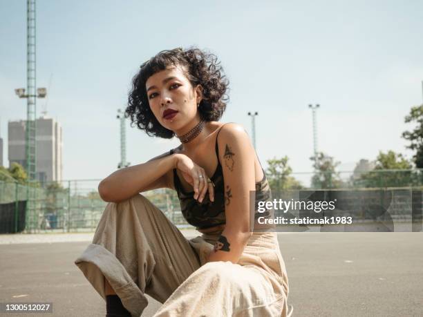 teenager-mädchen mit skateboard im park an einem sonnigen tag. - tattoo stock-fotos und bilder