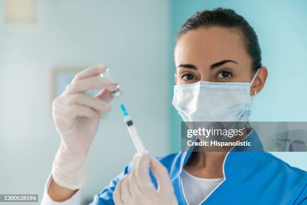 happy nurse preparing a covid-19 vaccine at the hospital - biosecurity stock pictures, royalty-free photos & images