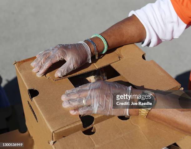 Volunteer prepares to place a box of groceries provided by the food bank, Feeding South Florida, into the vehicles of the needy at a distribution...