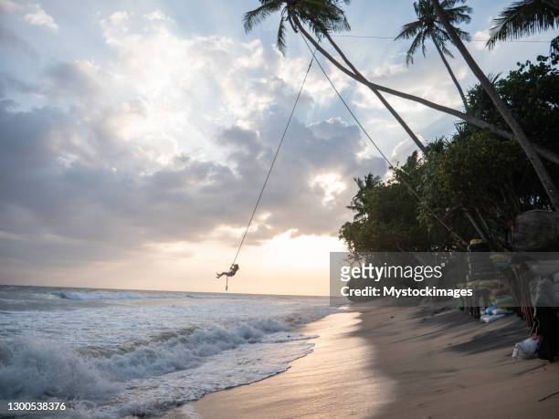 la donna gioca sull'altalena di corda sul mare - altalena di corda foto e immagini stock