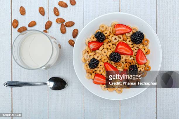 a bowl of cereal loops and a glass of milk with fresh fruit - cheerios stock-fotos und bilder