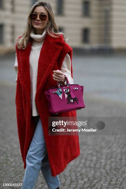 Mandy Bork wearing Bottega Veneta shades, red Max Mara Teddy vest, Hermes bag, H&M beige sweater and Marco Polo blue jeans on February 04, 2021 in...