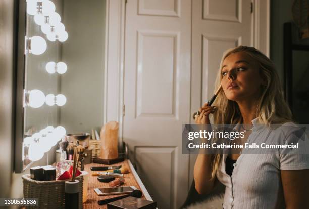 a young woman contours in front of an illuminated mirror - courbe photos et images de collection