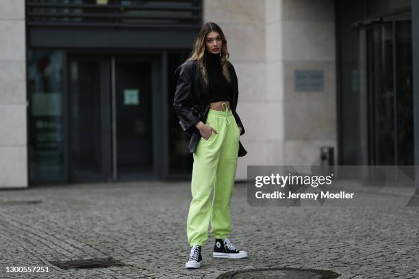 Sarah Posch wearing yellow neon Adidas jogging pants, Nakd black bag, H&M blazer, Zara crop turtleneck and Converse sneaker on February 04, 2021 in...