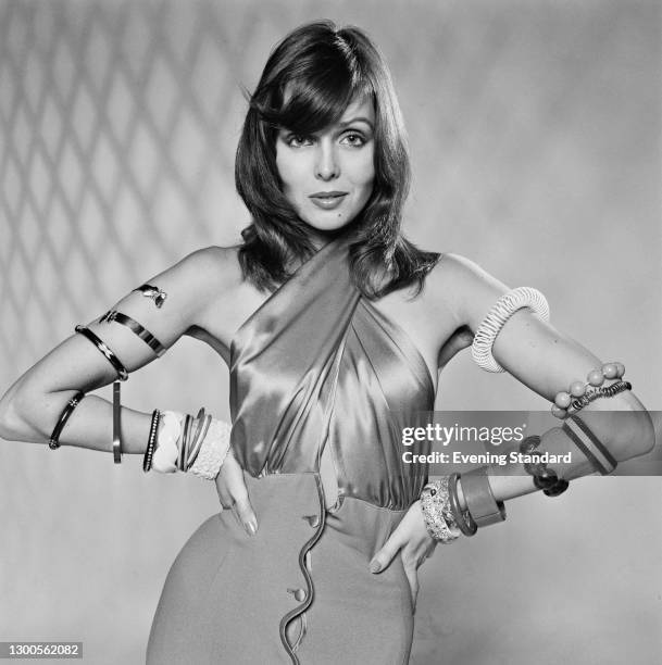 Model wearing a halterneck dress and a variety of armbands and bracelets, UK, 27th November 1973.