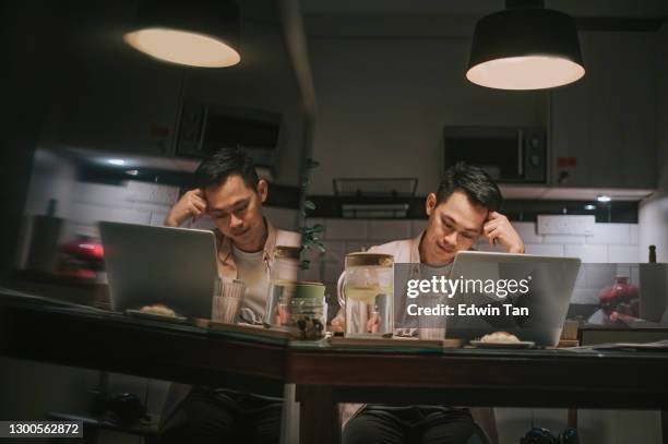 noche exceso de trabajo asiático asiático hombre trabajando hasta tarde en el comedor en casa estrés emocional con su factura financiera solo por la noche - recessed lighting fotografías e imágenes de stock