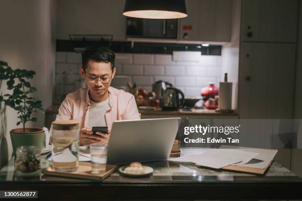 nachtüberarbeit asiatische chinesische männliche arbeit spät zu hause esszimmer emotionalen stress mit seiner finanziellen rechnung allein in der nacht - recessed lighting stock-fotos und bilder