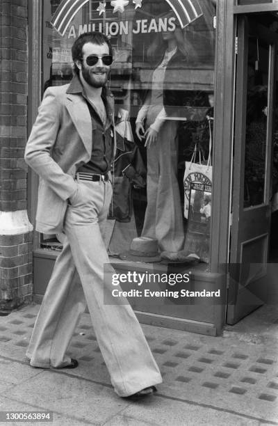 Bearded man wearing a denim suit with flared trousers, UK, 21st March 1973.