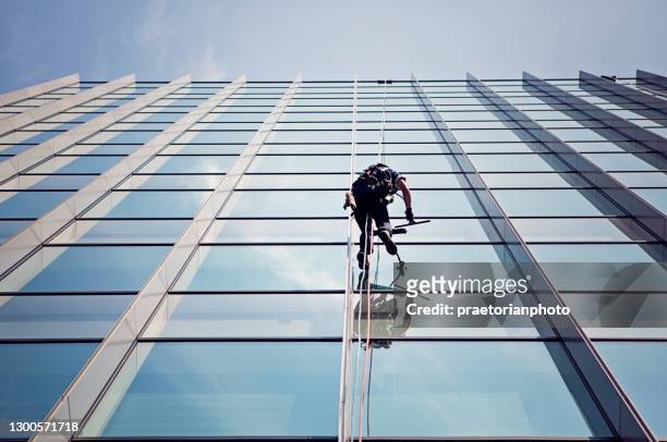 window cleaner is working on the office building facade - service level high stock pictures, royalty-free photos & images