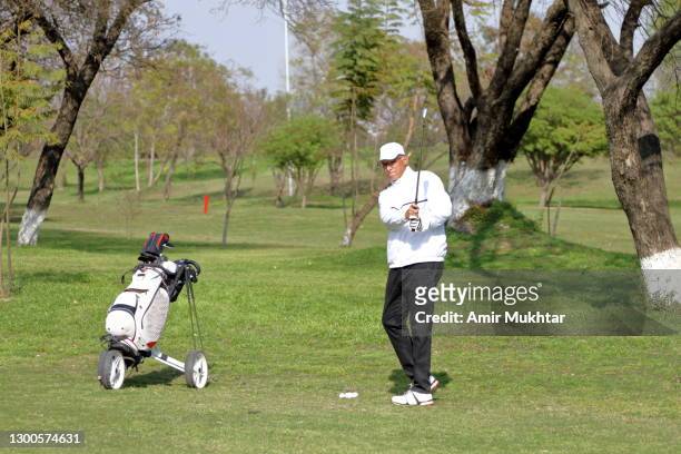 a golfer is swinging golf club after hitting golf ball in sunlight. - campo di allenamento foto e immagini stock