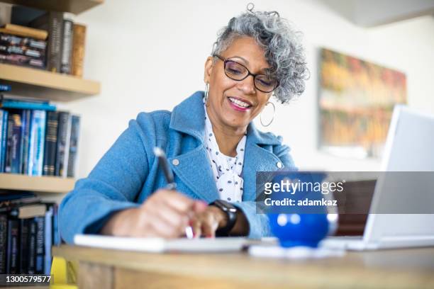 rijpe zwarte vrouw die van huis werkt - black woman laptop stockfoto's en -beelden