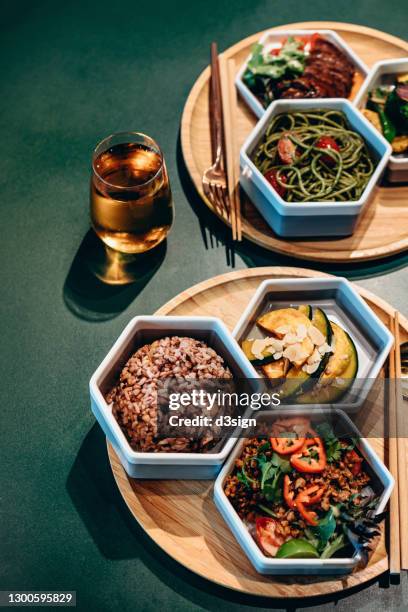 high angle view of fusion food meal sets with a glass of fruit juice freshly served on a wooden tray with nutritional ingredients to create a balanced and healthy diet, on a green dining table in a restaurant. farm-to-table, healthy eating concept - cucina fusion foto e immagini stock