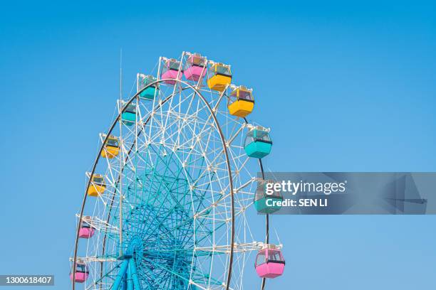 colorful ferris wheel in an amusement park against blue sky - amusement park sky fotografías e imágenes de stock